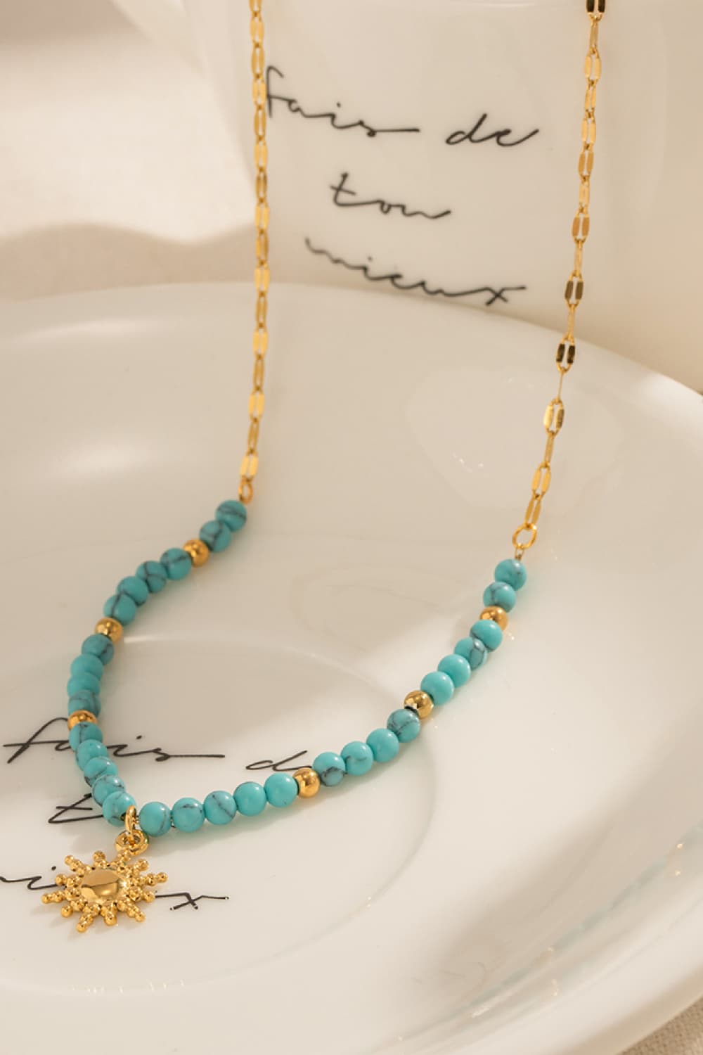 Turquoise beaded gold link necklace with sun pendant charm, close-up