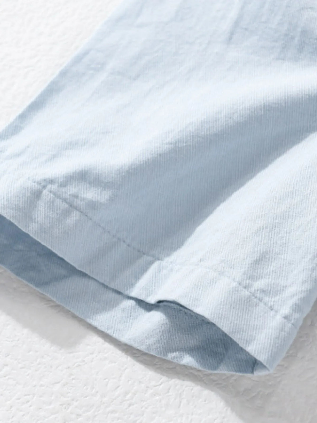 Men's short-sleeve cotton button-up shirt, light blue fabric and sleeve hem close-up