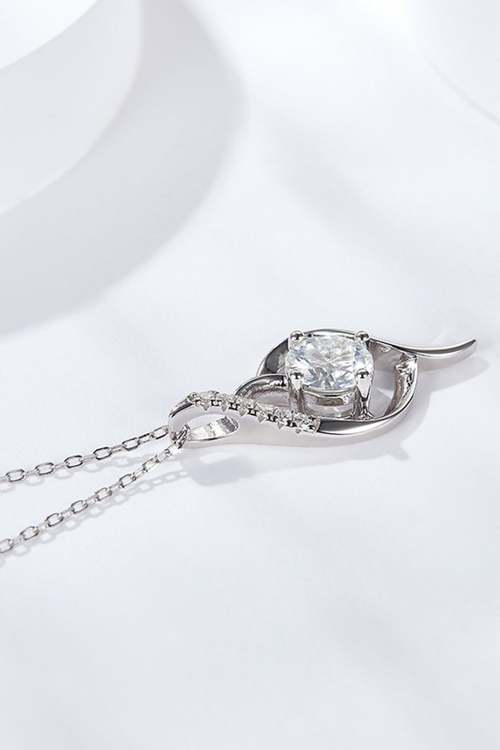 Silver moissanite pendant necklace with large center stone and small side stones on chain