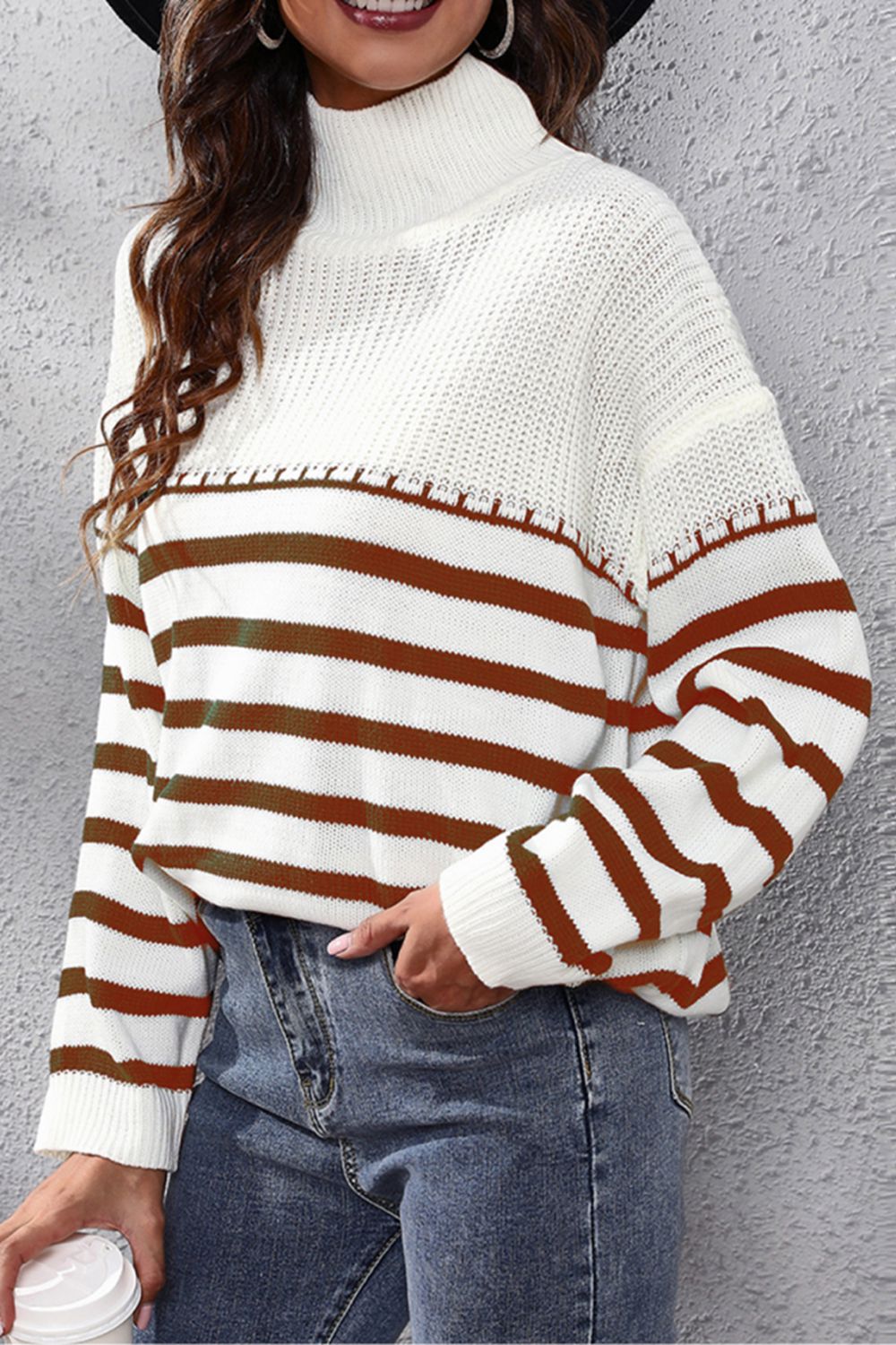 White knit turtleneck drop-shoulder sweater with brown and white horizontal stripes, close-up
