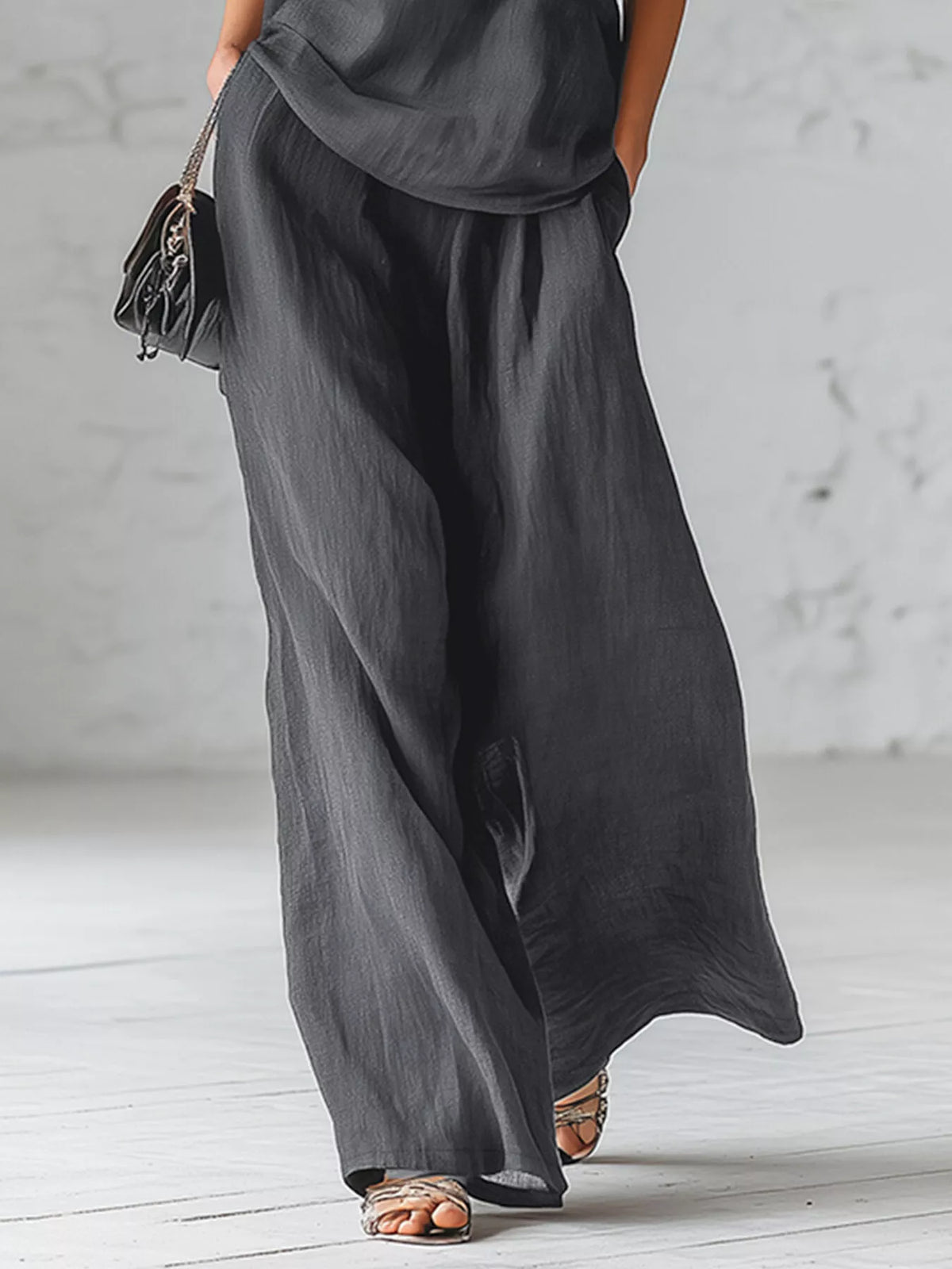 Gray wide-leg pants with draped one-shoulder bow top, side view