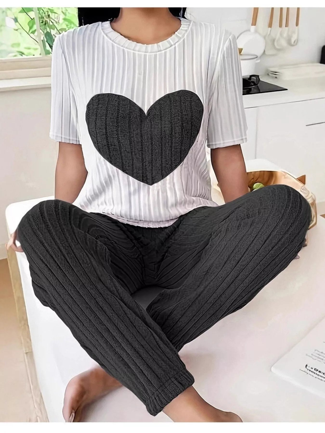 Heart ribbed knit lounge set with white striped top and black pants, seated view