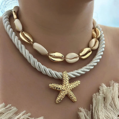 Gold starfish rope necklace with white shell beads and gold accents, close-up on skin