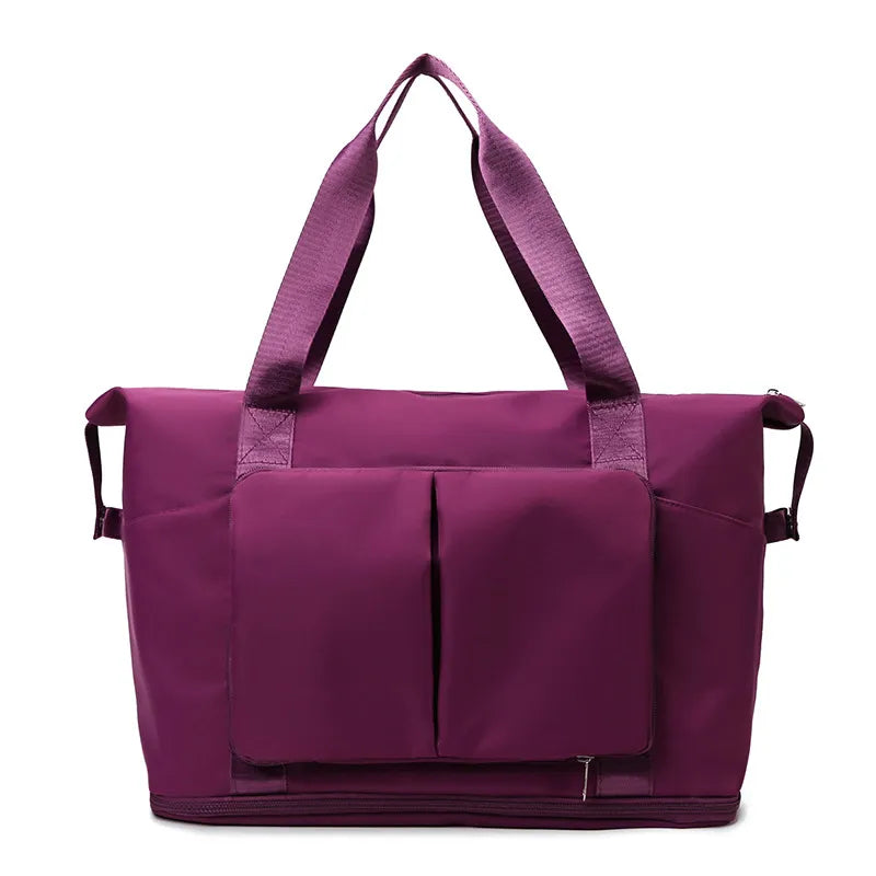 Plum purple travel duffel bag with front organizer pocket, top handles, and side carry straps.