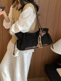 Black suede drawstring shoulder bag with brown trim and hanging tassel pull cords