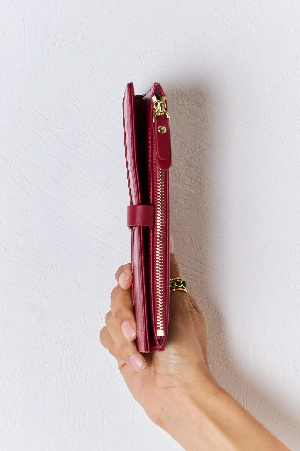 Red textured PU leather wallet with side zipper and gold-tone zipper pull, held upright.