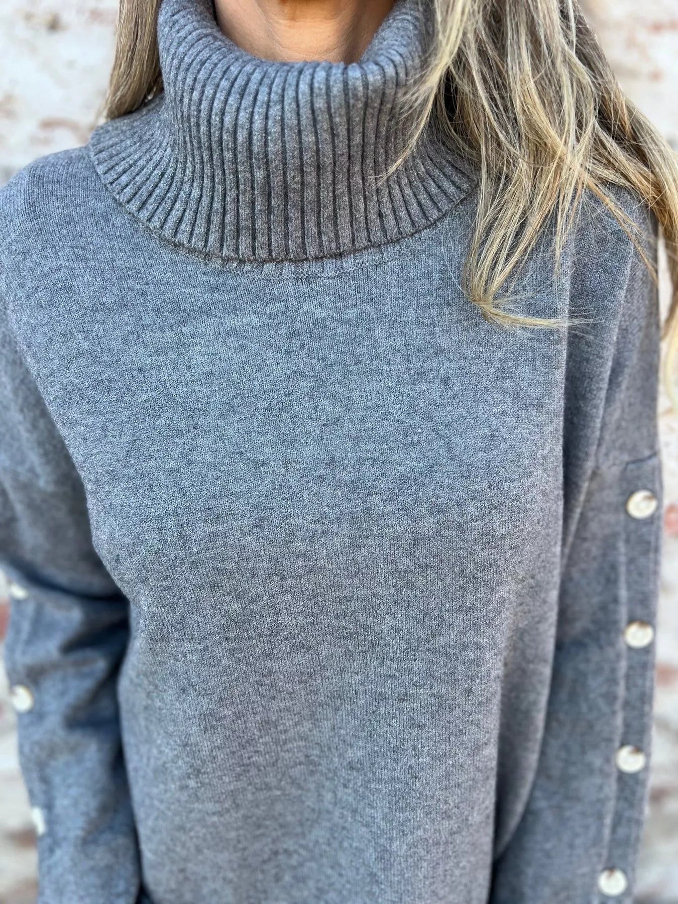 Heather gray turtleneck sweater with ribbed collar and buttoned shoulder sleeve detail