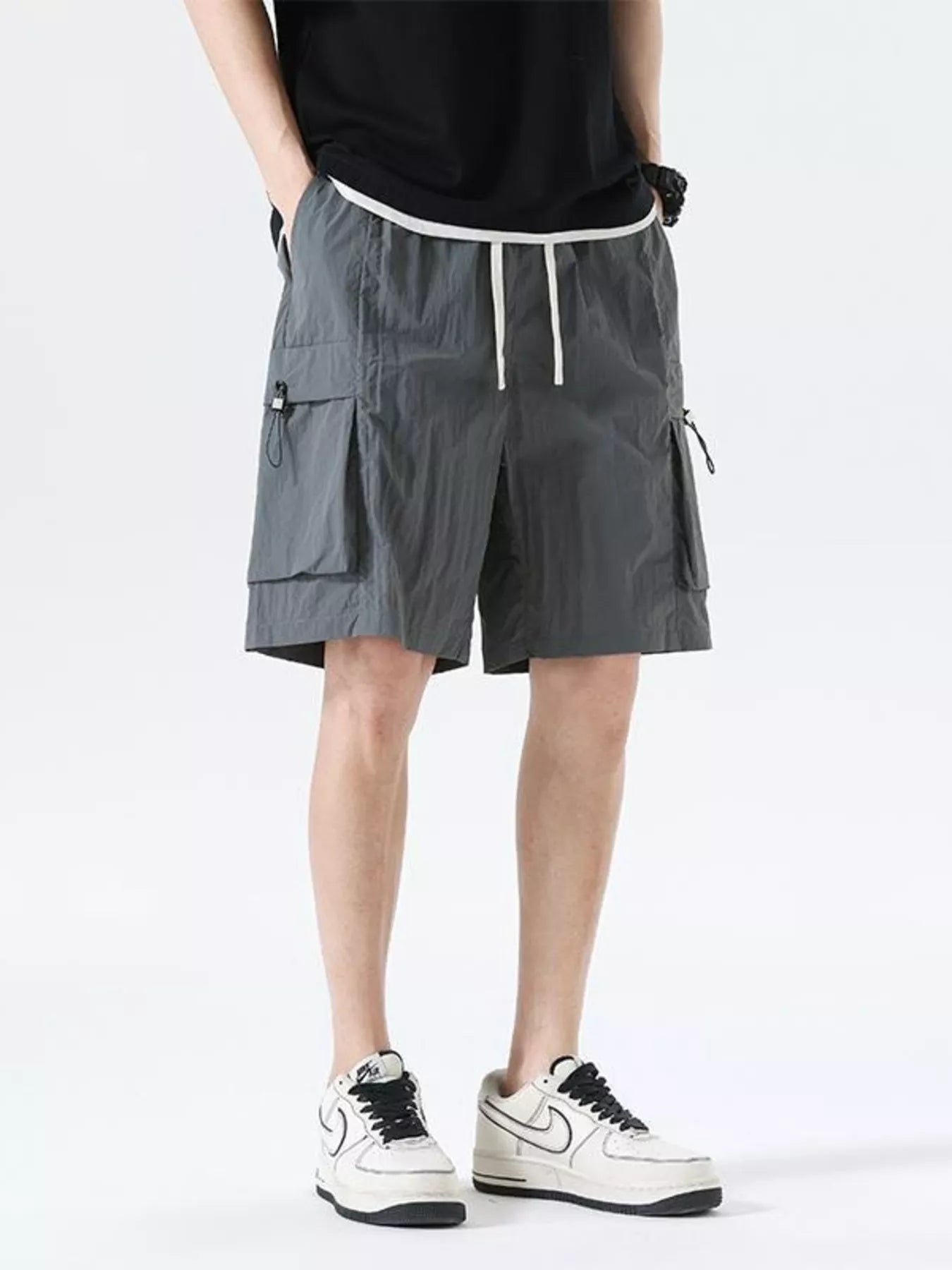 Grey drawstring cargo shorts with side flap pockets and cargo leg panels
