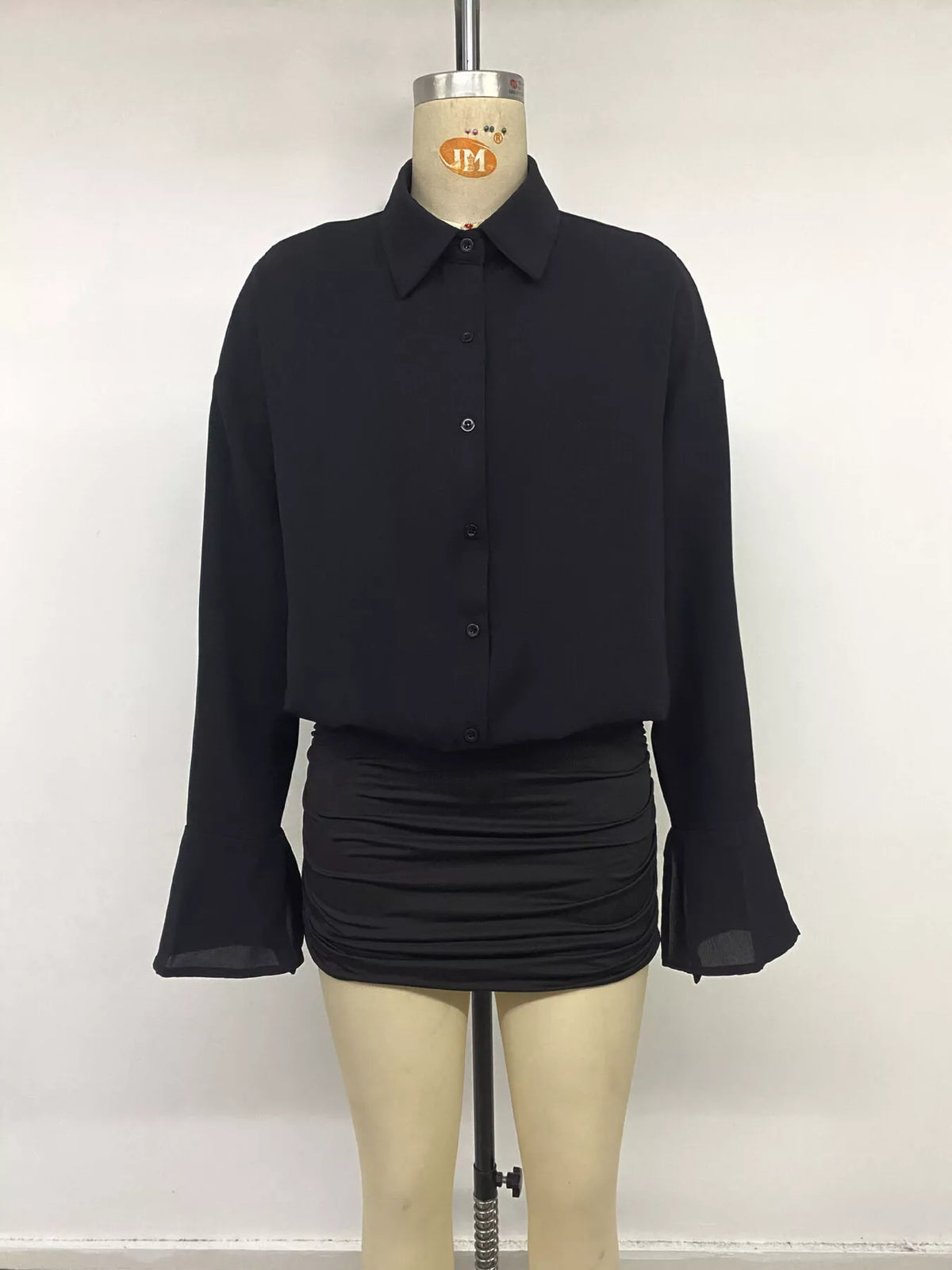Black shirt dress on a mannequin: collar, buttons, and ruched mini skirt