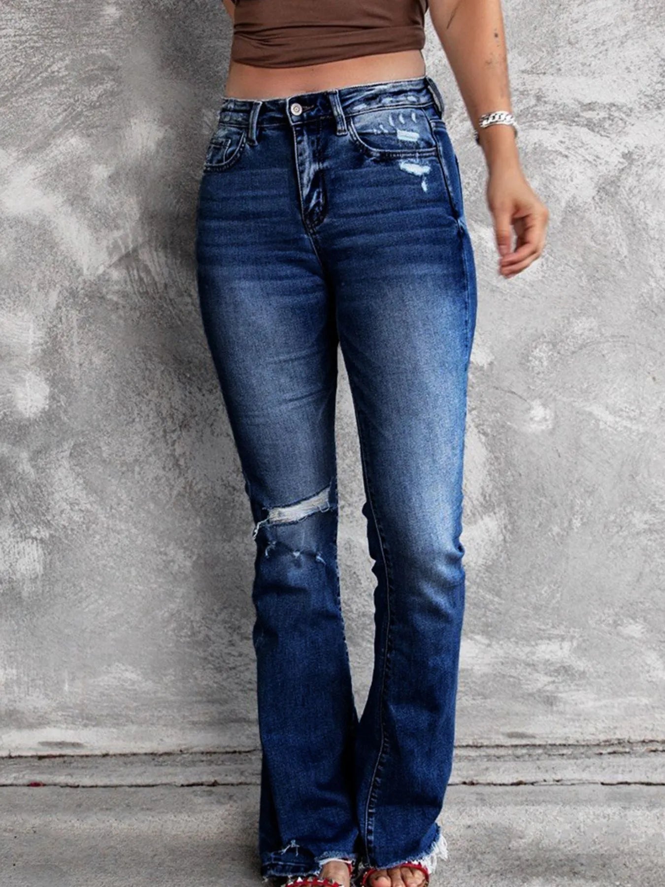 Medium blue distressed flare jeans with knee shredding and worn fade along the thighs
