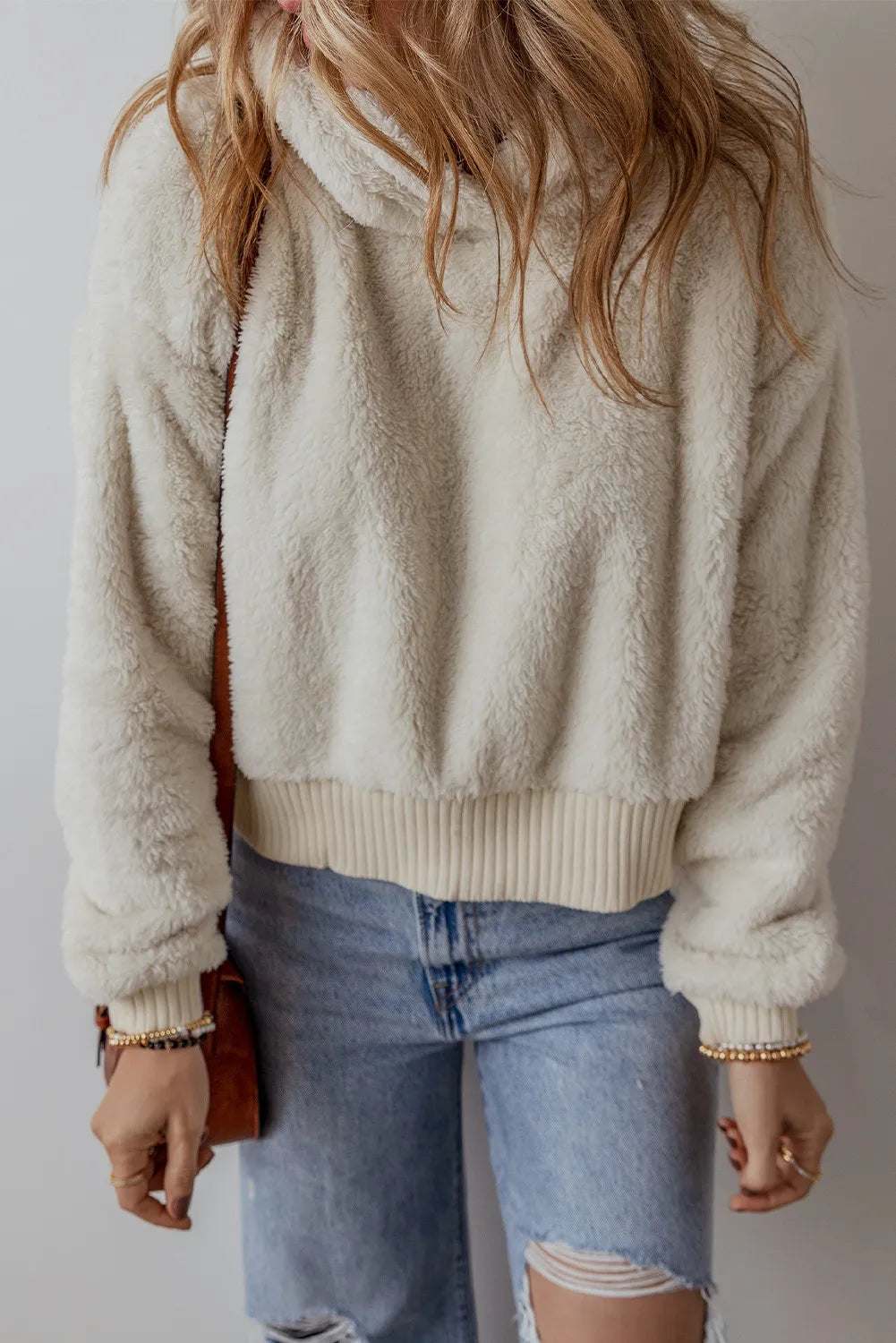 Beige fuzzy hoodie with hood and ribbed hem, dropped shoulders, paired with light jeans