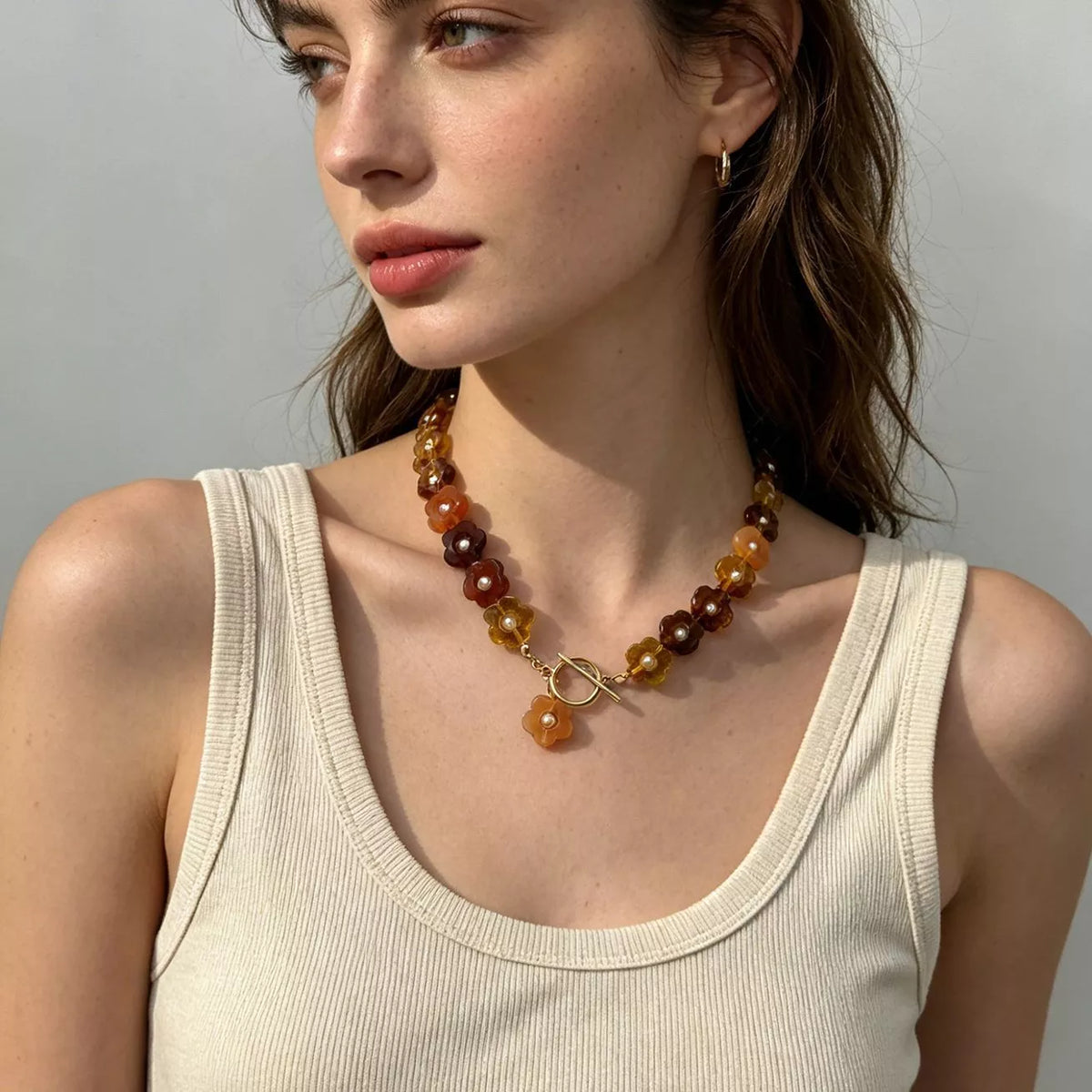 Gold beaded necklace with resin flower accents and small gold loop clasp at center