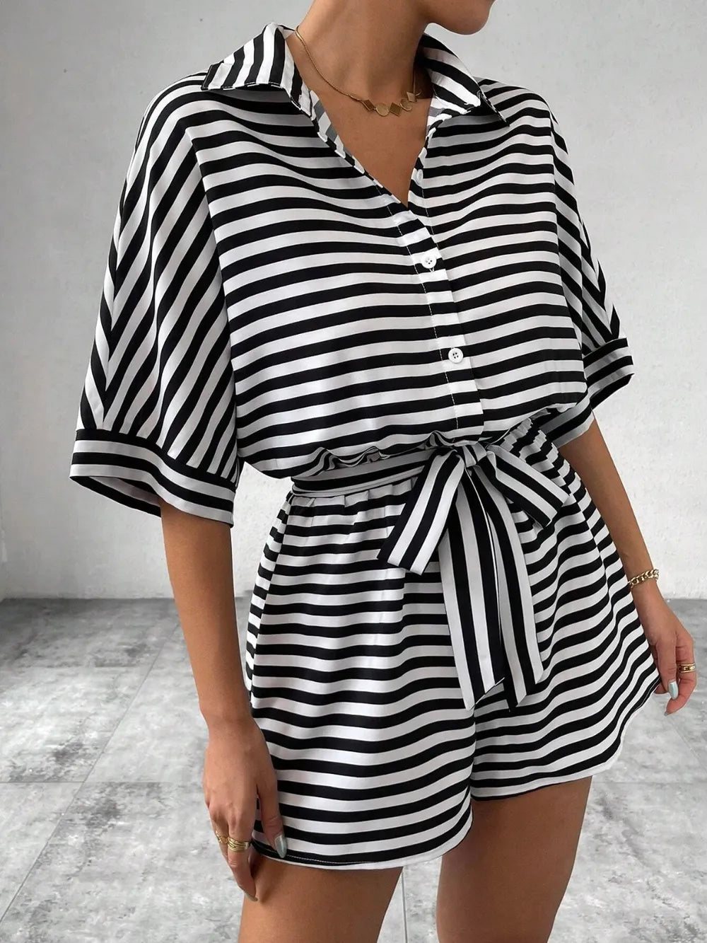 Black and white striped button-front romper with tie belt at waist and cuffed short sleeves