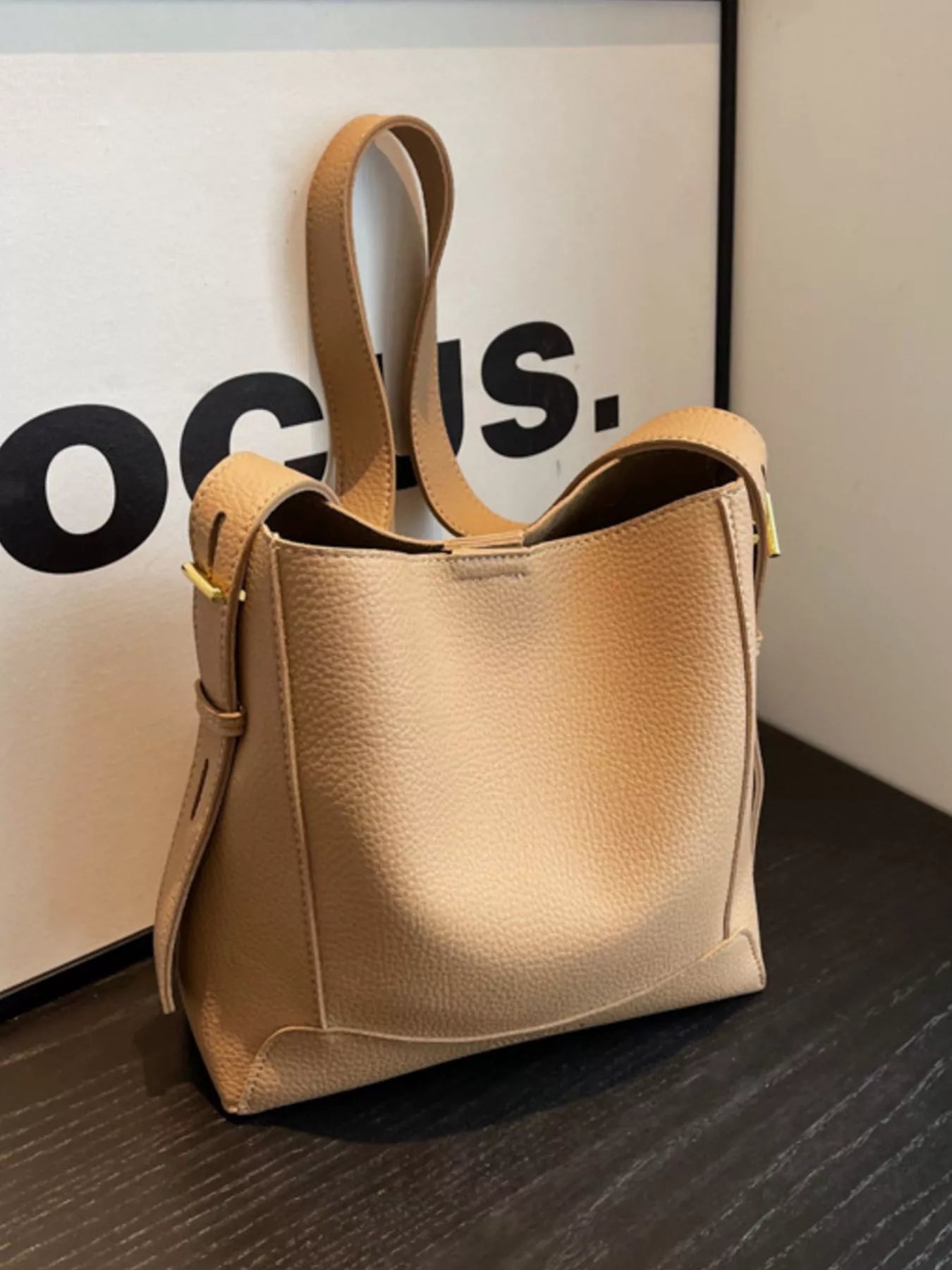 Khaki leather crossbody bag with adjustable strap, gold hardware, and rounded top