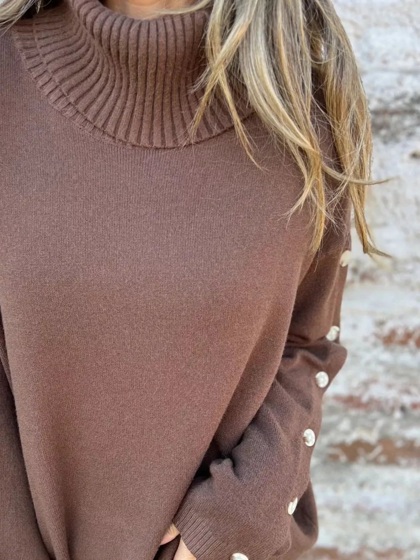 Mocha-brown turtleneck sweater close-up of ribbed collar and buttoned cuffs