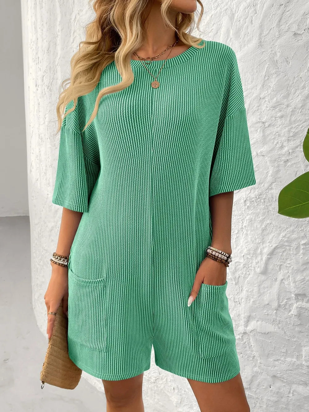 Textured green romper with round neck, half sleeves, and front patch pockets