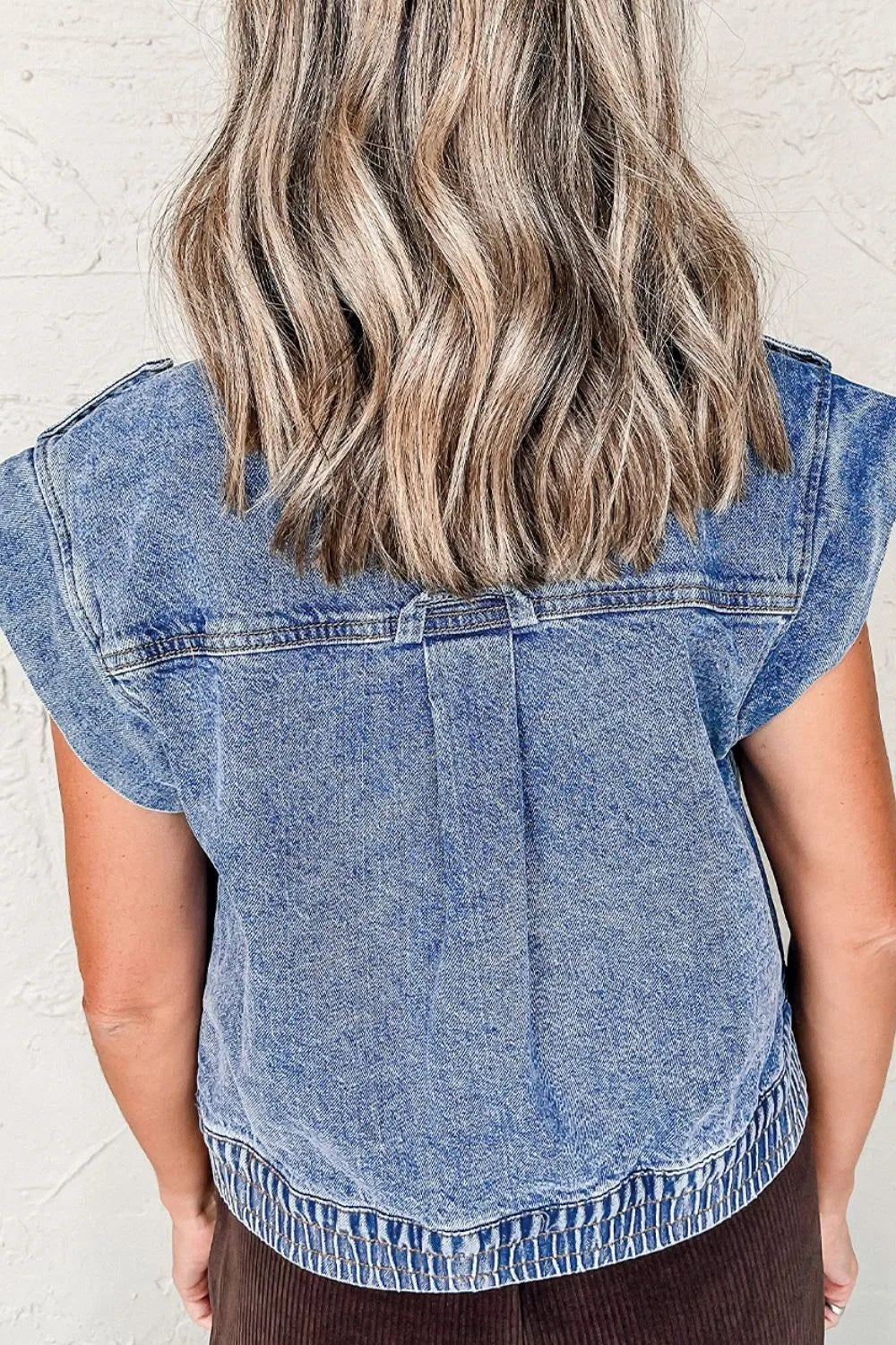 Medium-wash denim button-up cap sleeve jacket, back view with stitched yoke and hem trim