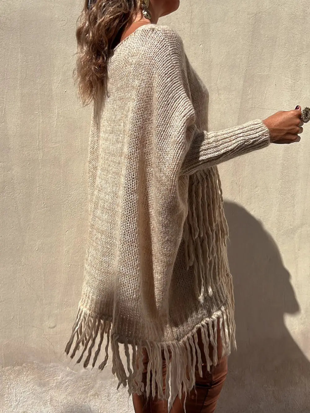 Camel long-sleeve sweater side view with fringe cuffs and hem and pocket panel detail.