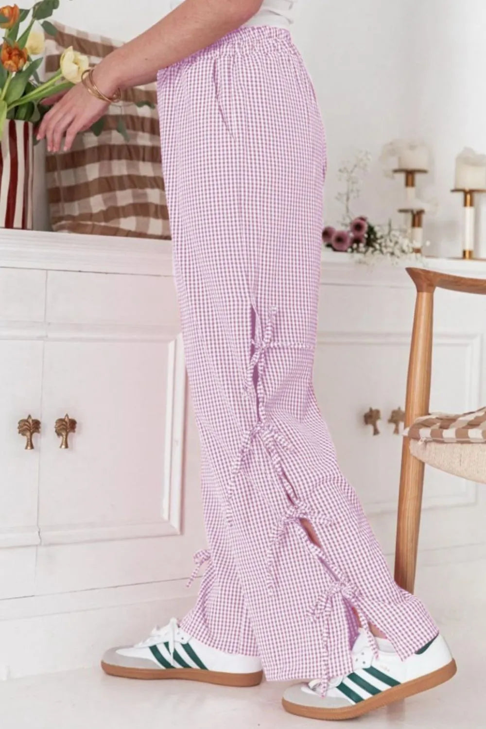 Pink gingham wide-leg pants with tied front slit and tassel side trim