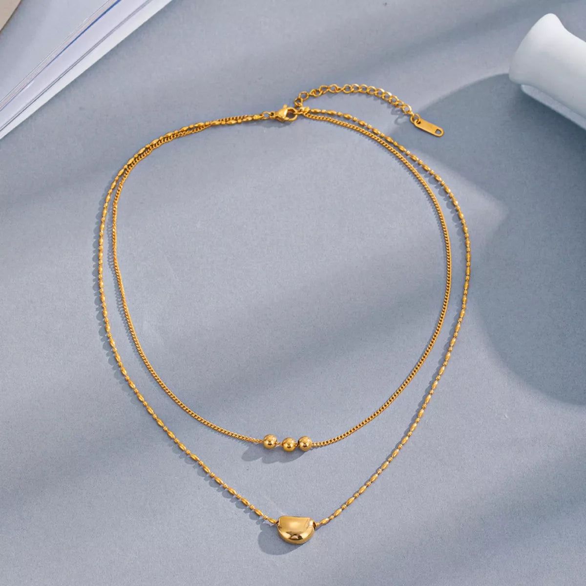 Gold double-layer necklace set with heart drop pendant and small clustered beads near center.