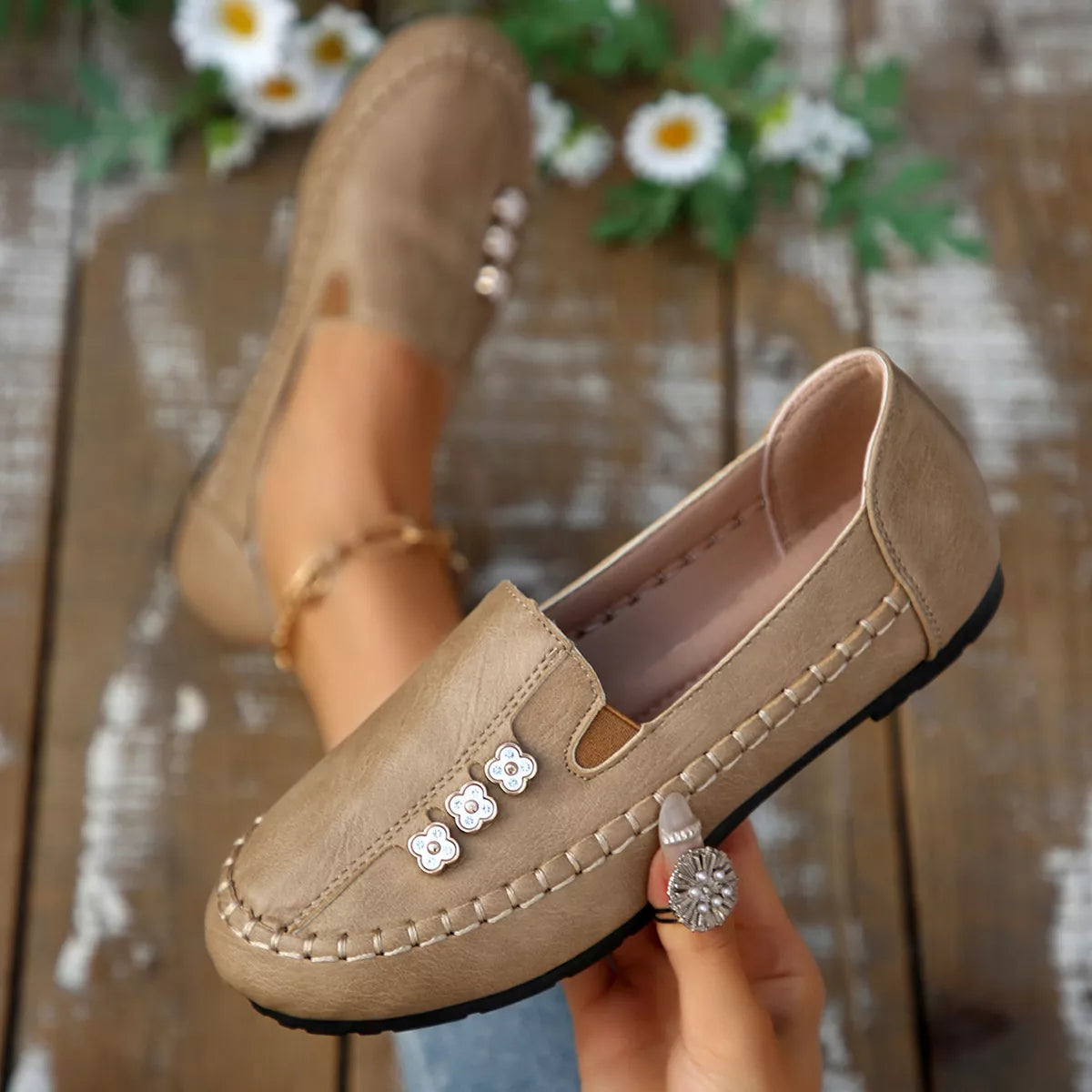 Beige round-toe slip-on flats with floral embellishment across the front