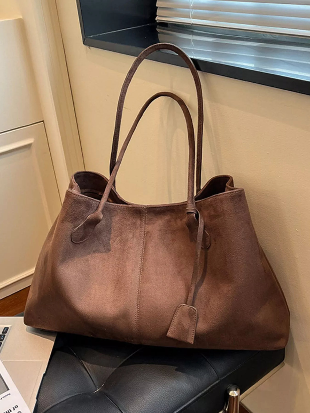 Brown suede tote bag with dual handles and front flap pocket detail