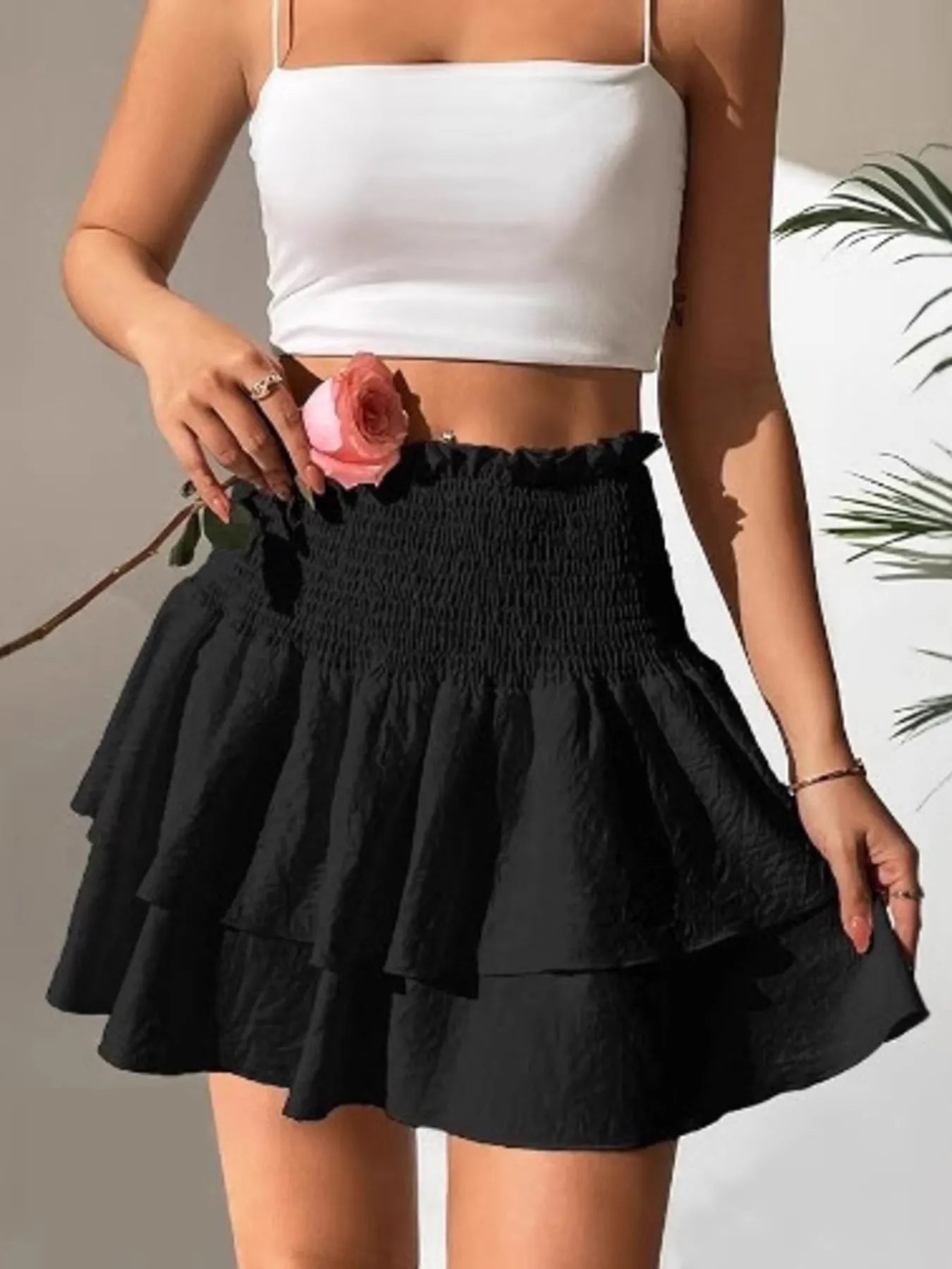 Black tiered smocked mini skirt with gathered waistband and layered skirt panels