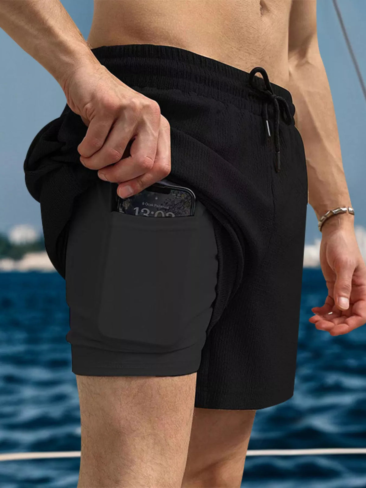 Black drawstring shorts with side pockets and elastic waistband, mid-thigh length