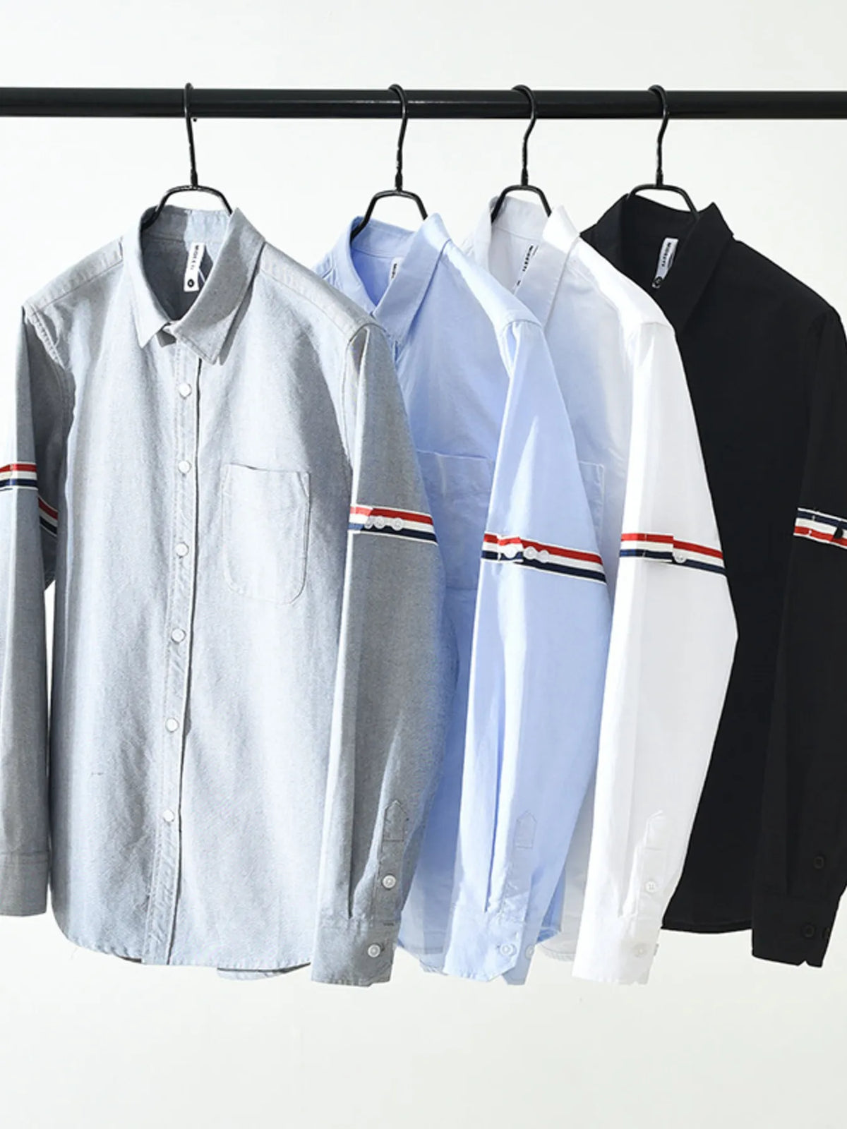 Men's classic button-up shirts on hangers in white, light blue, grey, and black
