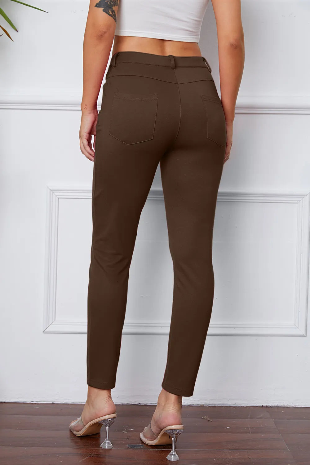 Brown slim ankle pants with belt loops, front button, back pockets, and stitched seams