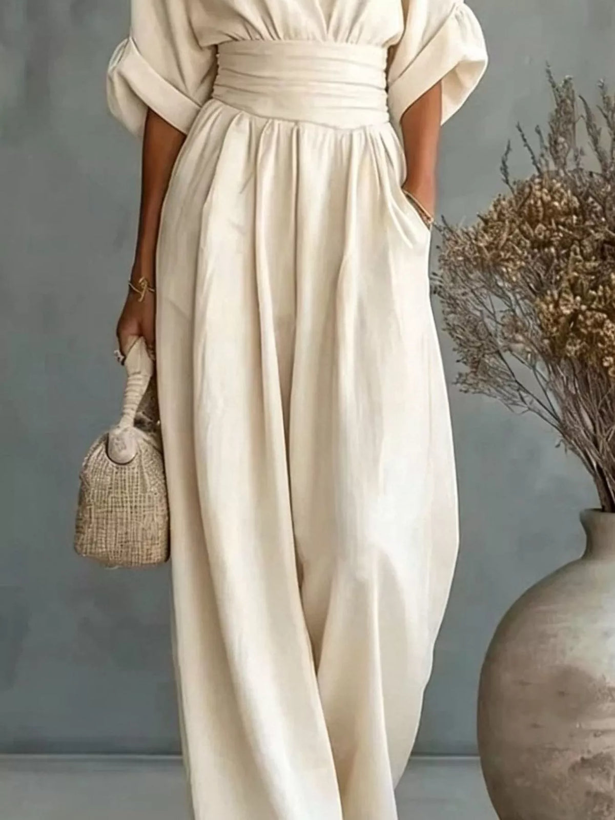 Beige wide-leg jumpsuit with V-neck and cinched waist, flowing wide pant legs