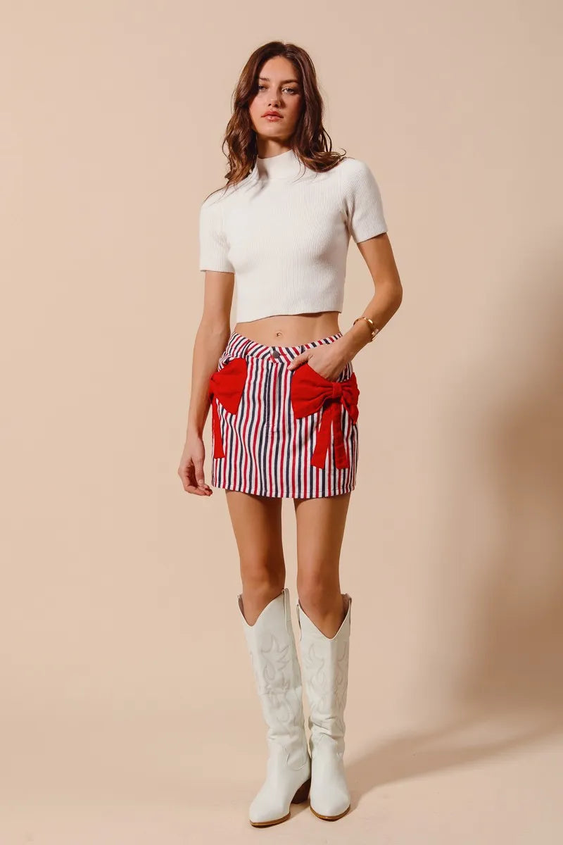 Striped denim mini skirt with red bow tie and tassel pocket accents at front