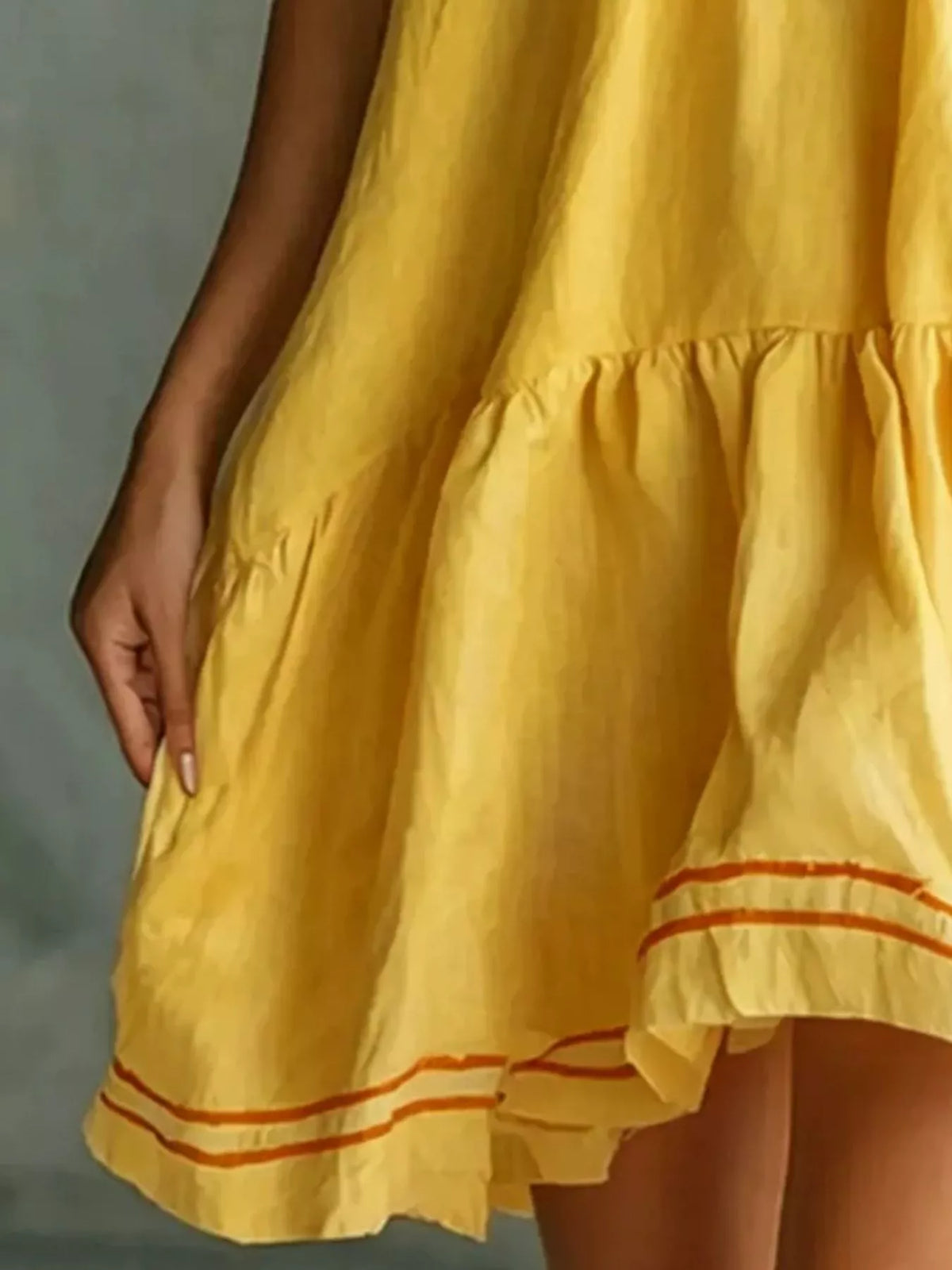 Close view of yellow tiered ruffled mini dress with red striped trim