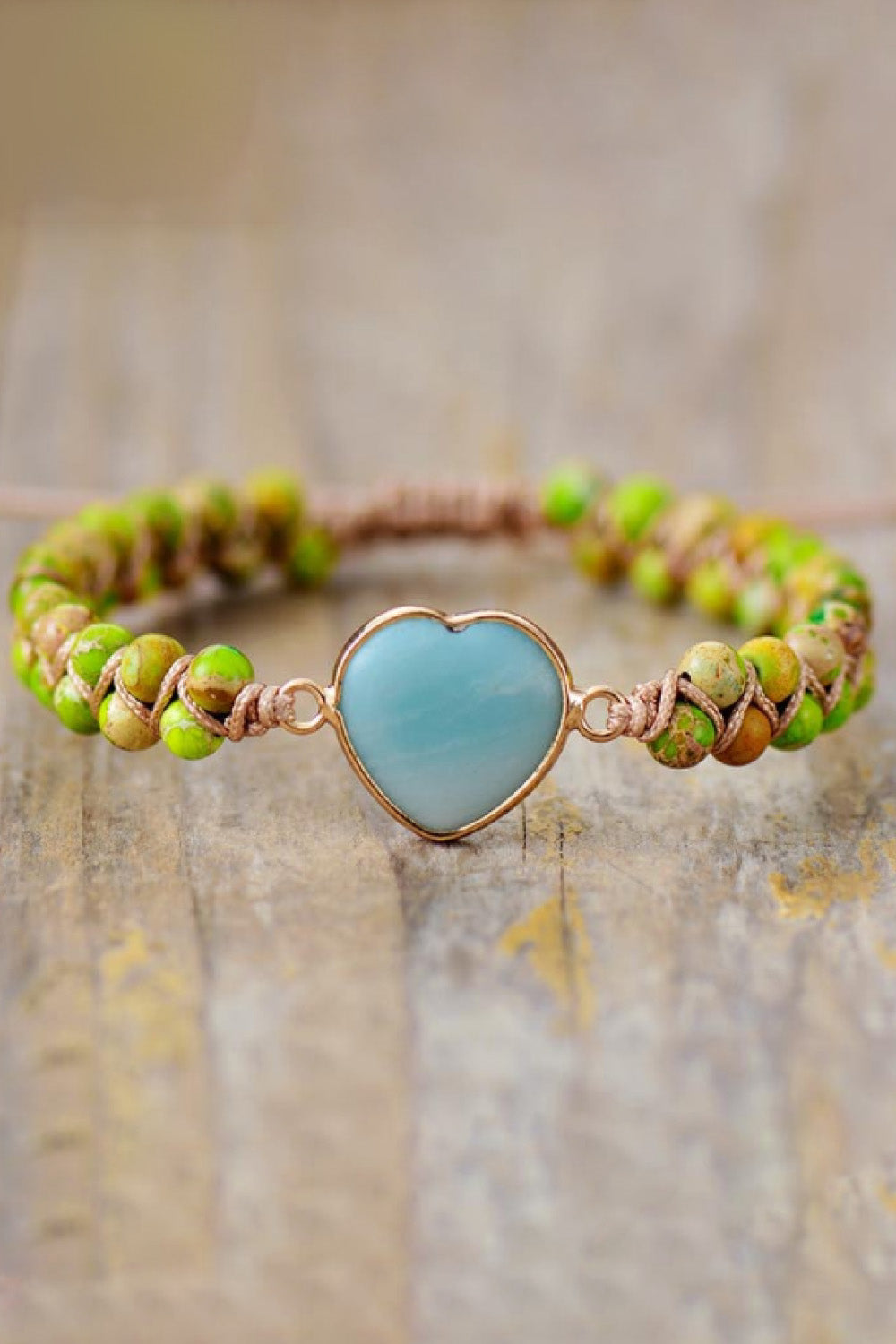 Green bead braided bracelet with gold heart-shaped pendant and light blue stone center