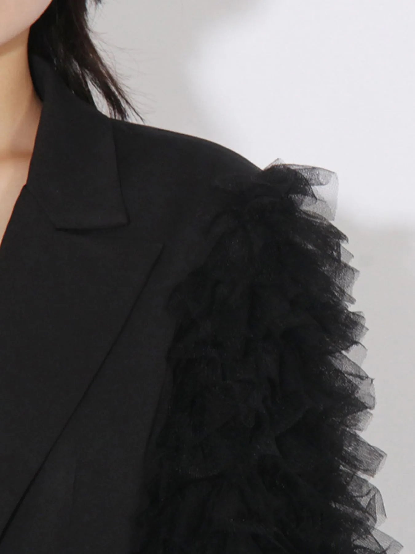Black blazer sleeve close-up with fluffy tulle texture trim