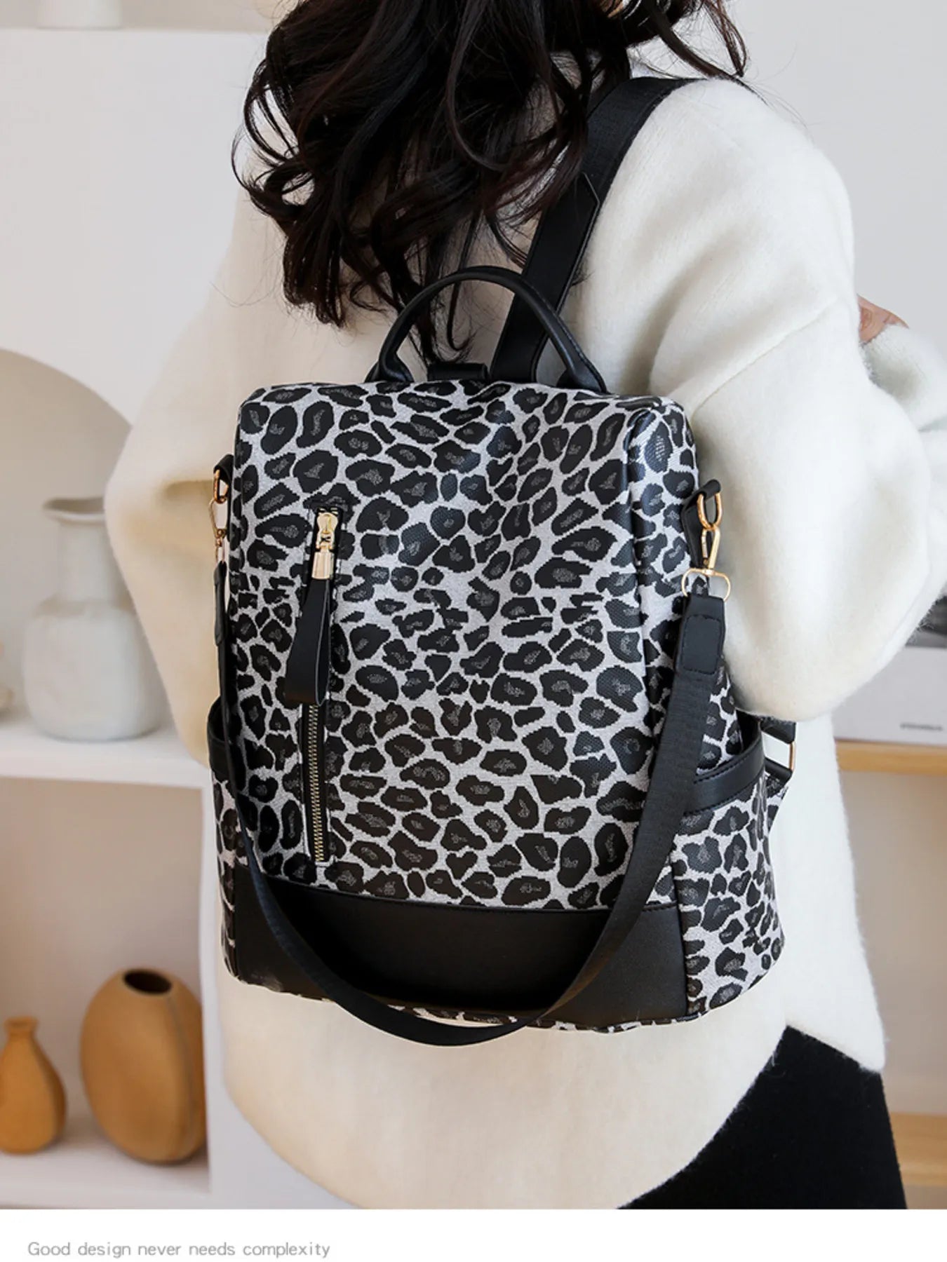 Leopard print backpack with black straps and front zip pocket, side view.
