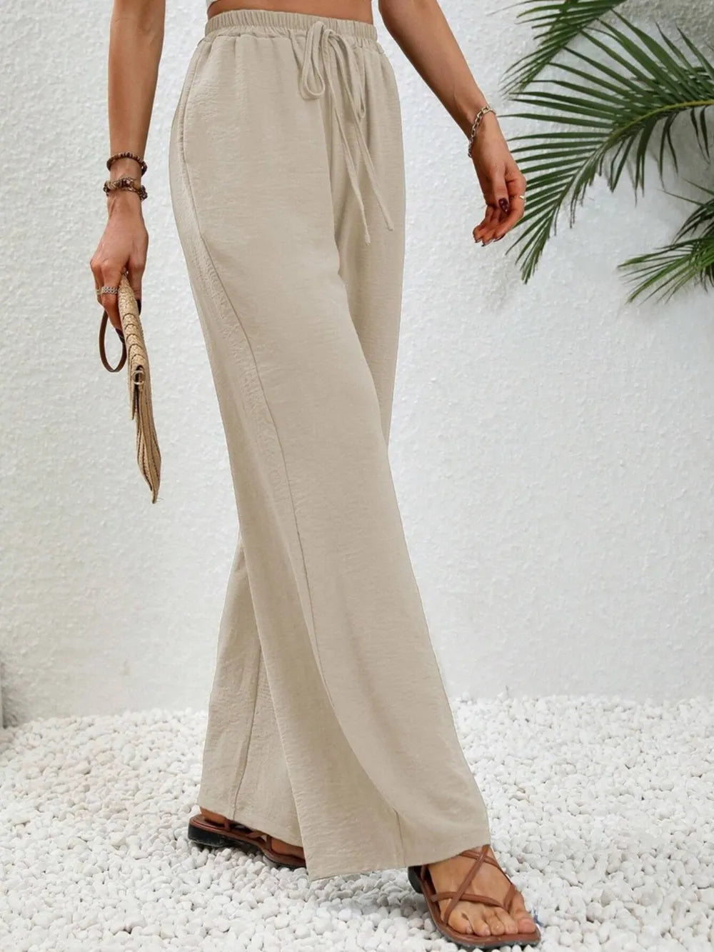 Cream wide-leg drawstring pants with elastic waist and tapered-to-wide drape