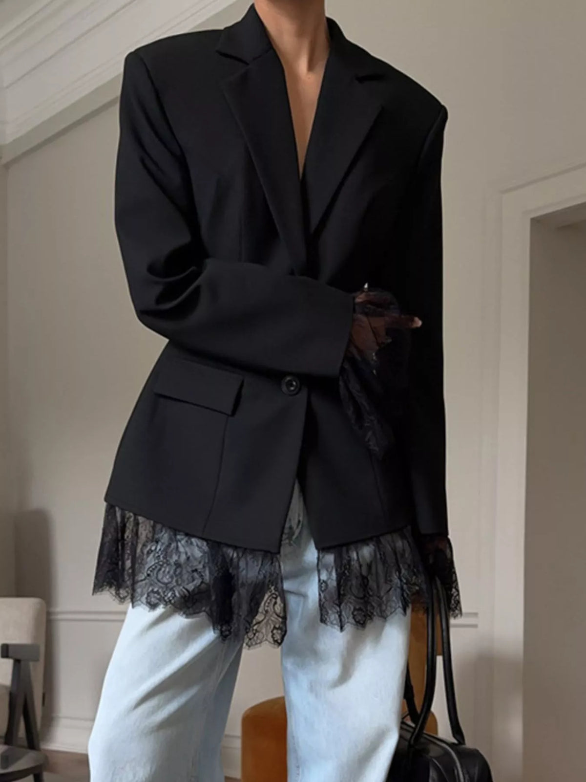 Black women’s blazer with lace bottom trim, notch lapels, and flap pockets.