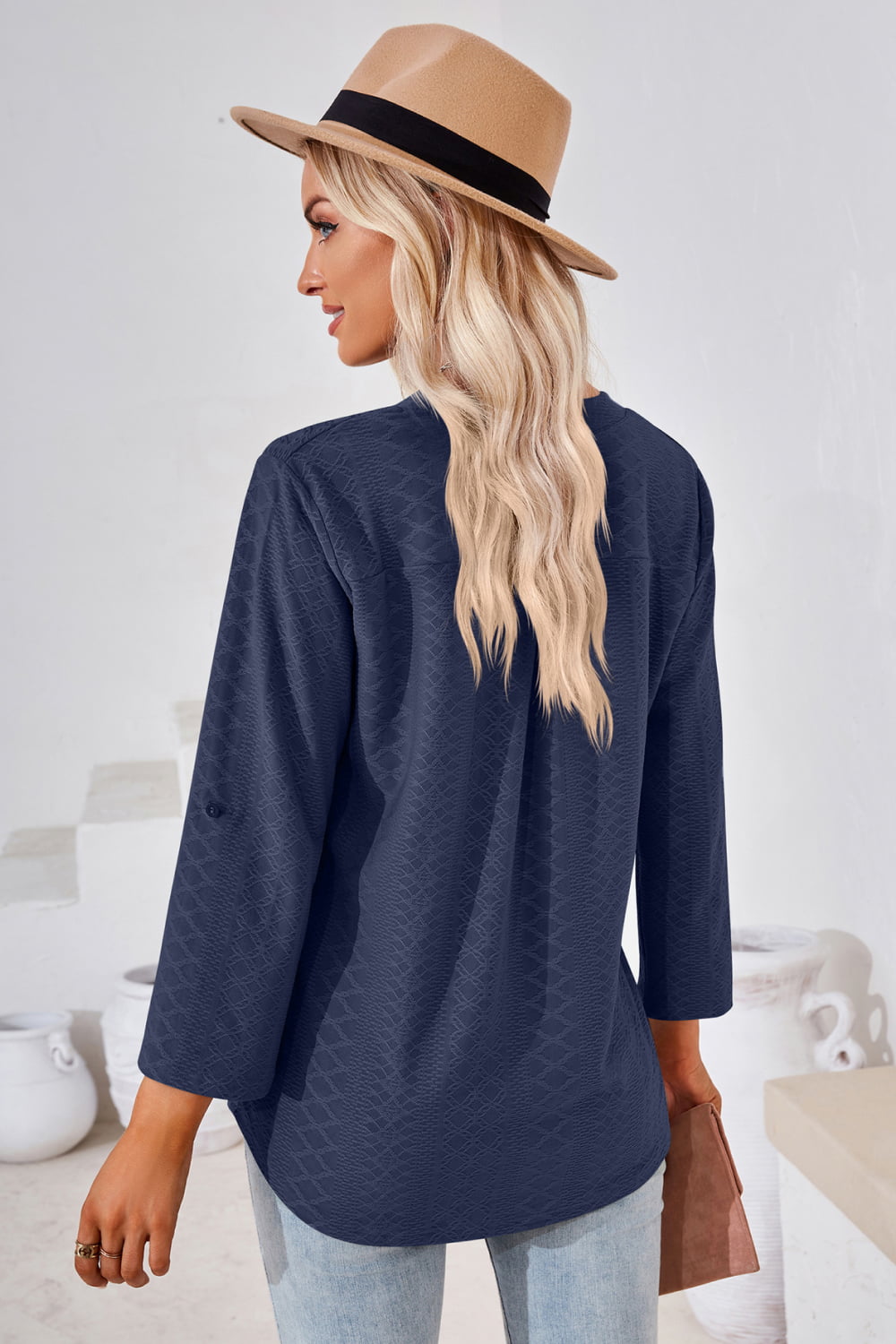Dark blue V-neck blouse with roll-tap sleeves and textured fabric design.