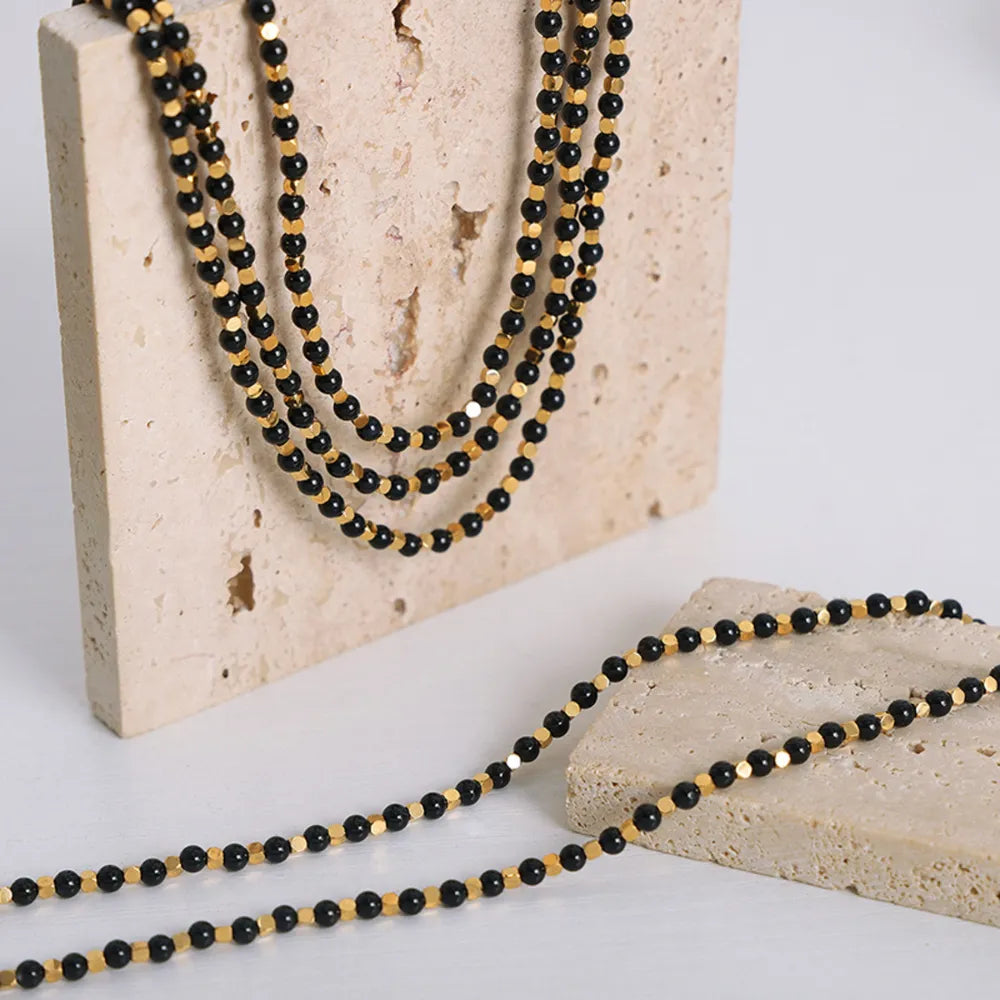 Agate beaded necklace with three rows of black beads and gold-tone accents