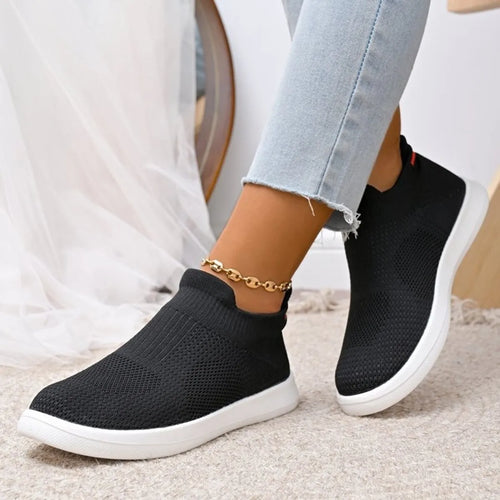 Black breathable knit slip-on shoes with white sole, worn with ankle bracelet