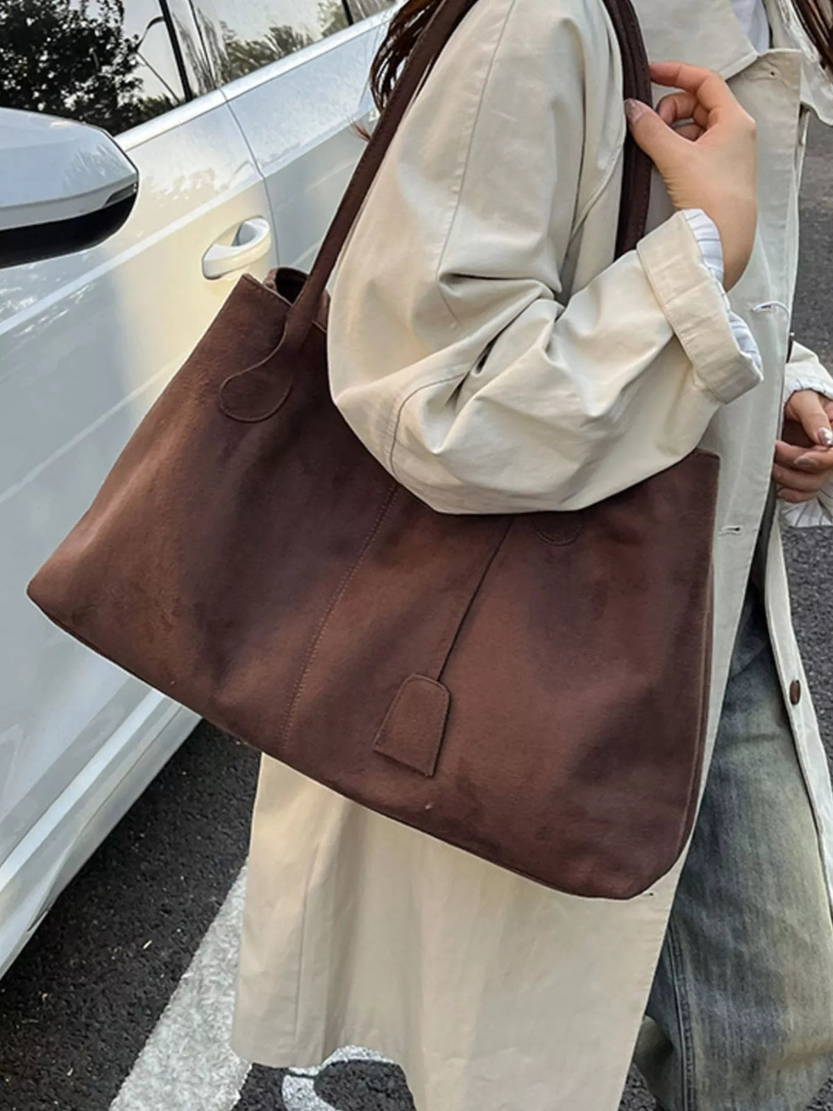Brown suede tote bag with dual handles and front flap pocket on model