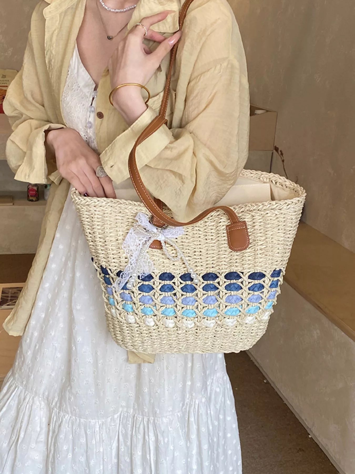 Woven straw shoulder bag with blue lattice stripe, brown leather top handle and bow charm