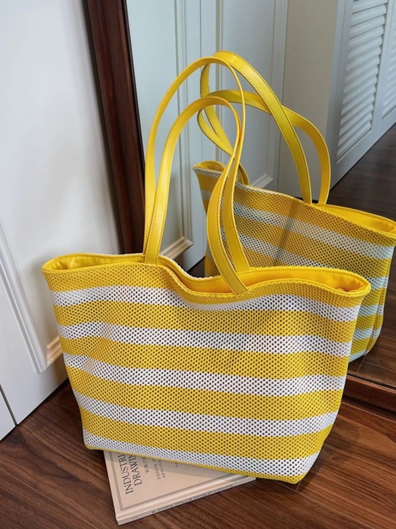 Yellow and white striped mesh tote shoulder bag standing upright, long handles