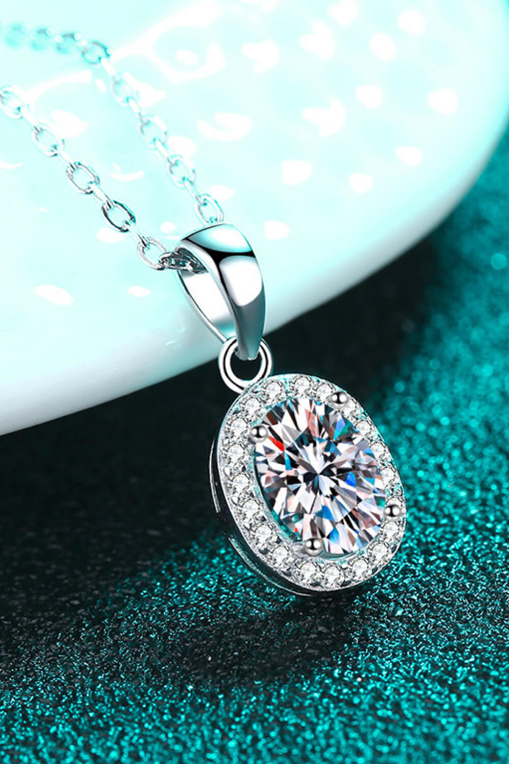 Silver moissanite oval pendant with halo setting, hanging on chain