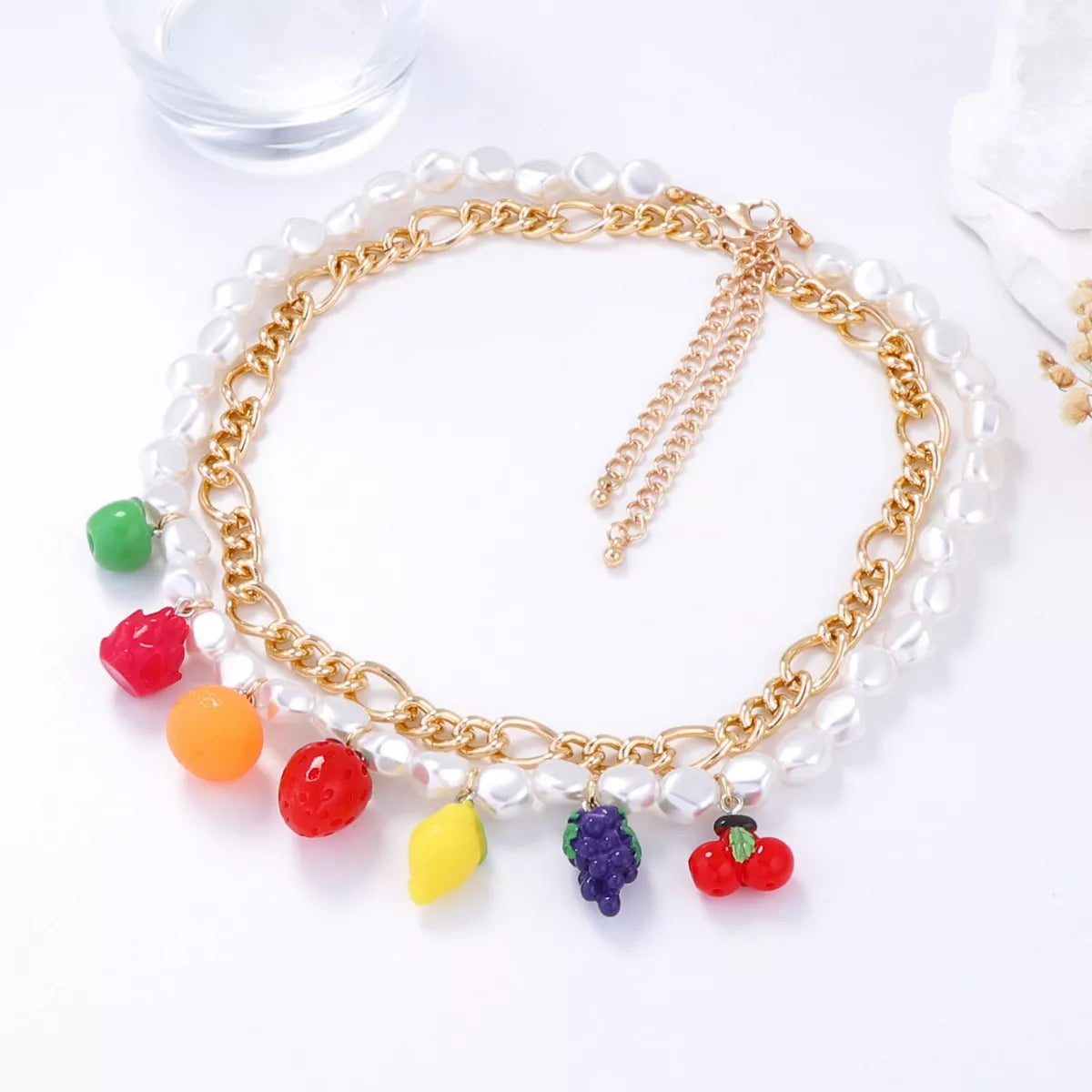 Double-layer charm necklace with gold chain, white pearls, and mixed fruit charms