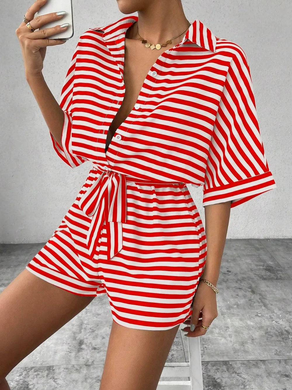 Red and white striped button-front romper with tie waist and cuffed short sleeves