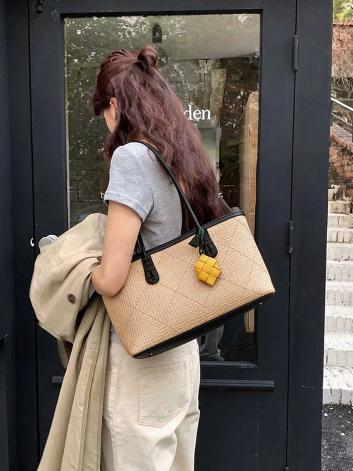 Beige leather shoulder bag with brown trim, black straps, and yellow charm