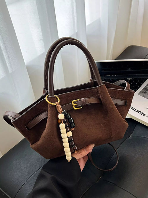 Brown suede tote bag with buckle front, top handles, and bead charm tassel