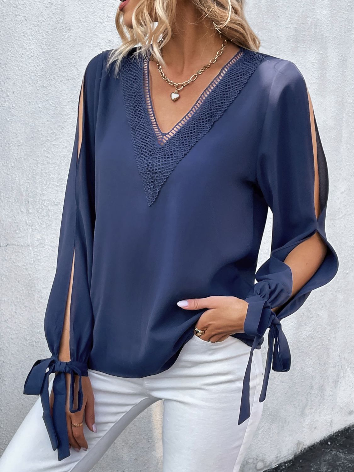 Dark blue V-neck blouse with crochet trim and long sleeves tied at the cuffs